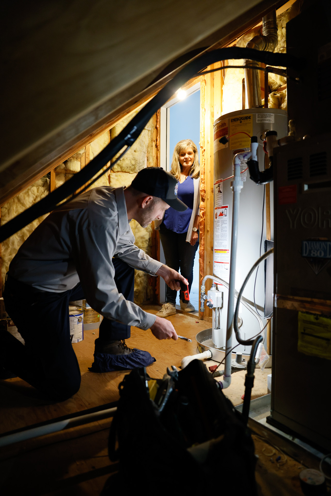 A hand turning a black knob on a white water heater.